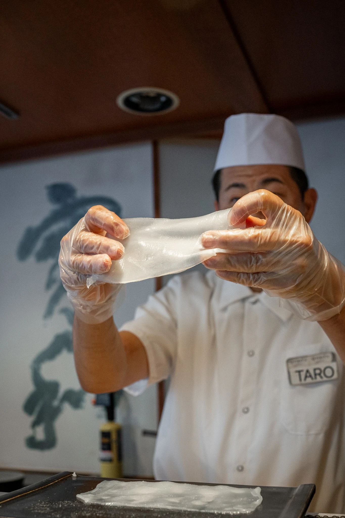 Sushi Chef Taro holds up thinly cut sheet of king squid
