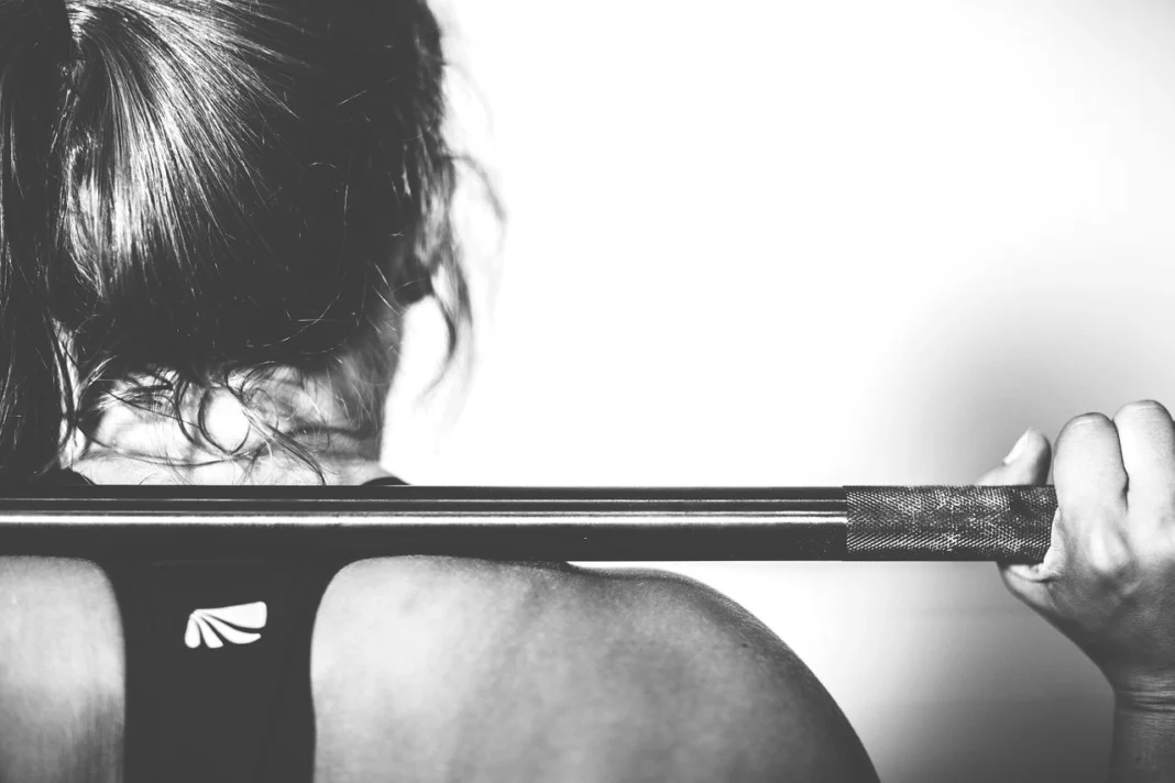woman lifting weights squats at gym