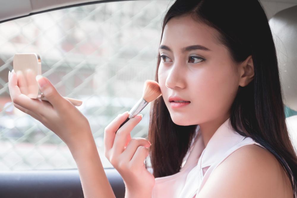 woman applying make up in car skincare