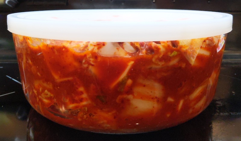 kimchi fermenting in large glass container