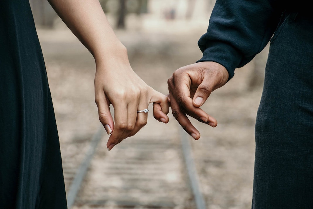 man in long sleeve top holding woman with wedding ring on finger