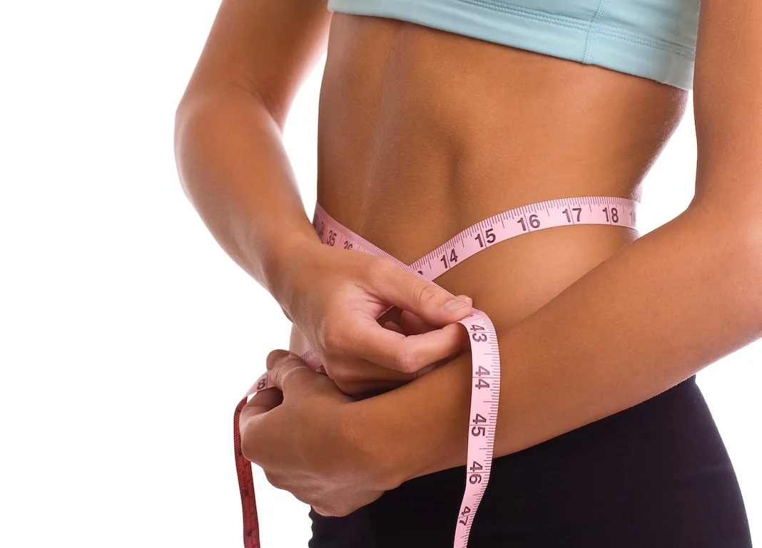 woman using measuring tape to measure waist size