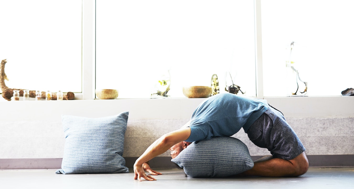 man doing a yoga backbend with pillow supports