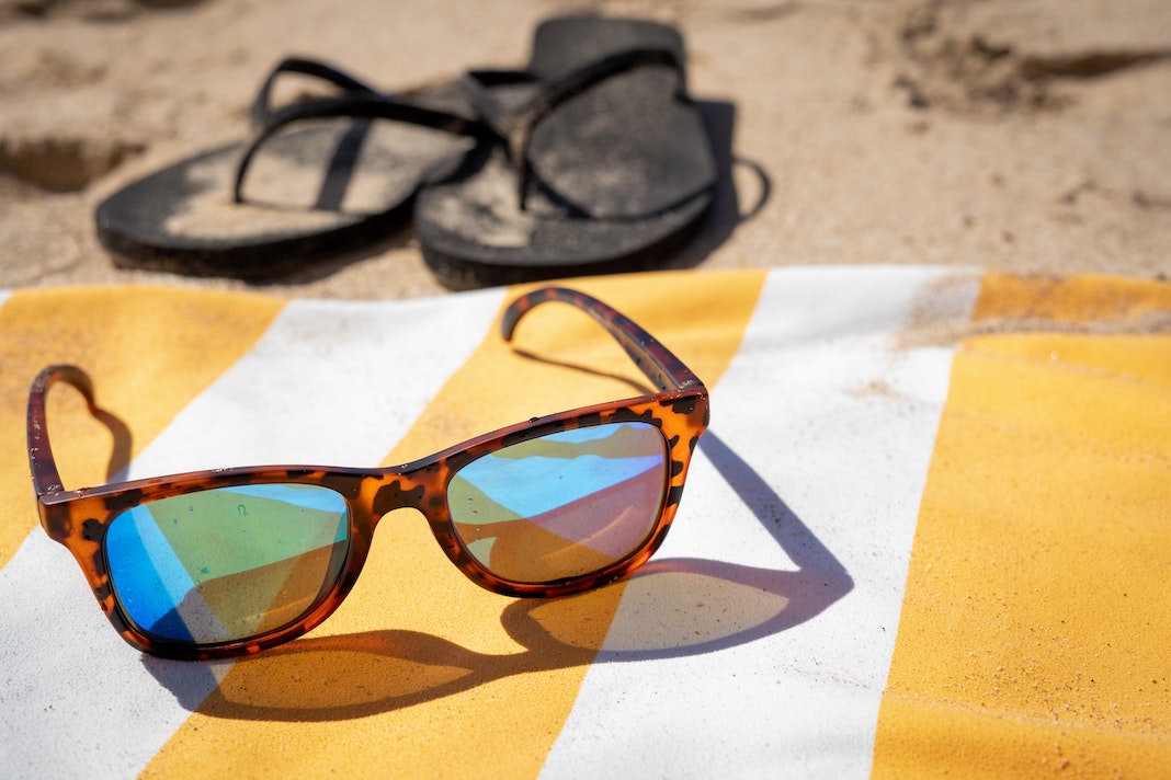Rheos floating sunglasses Rothys flip flop sandals on a beach