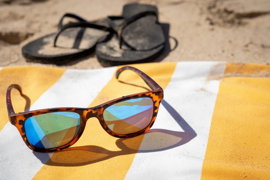 Rheos floating sunglasses Rothys flip flop sandals on a beach