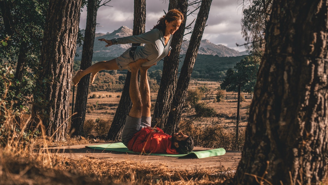 couple doing acro yoga in park area