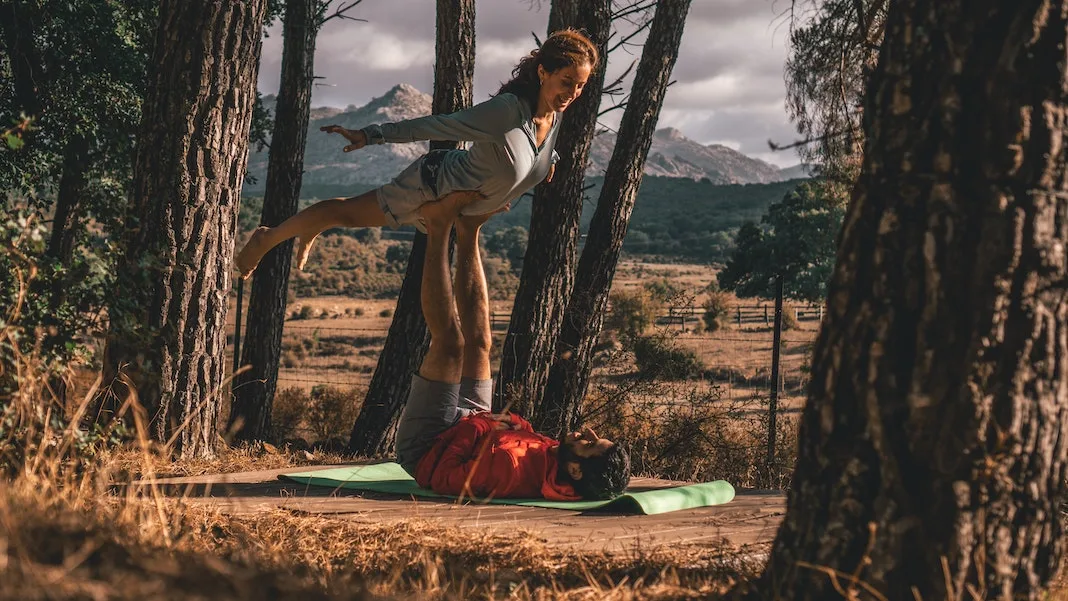 couple doing acro yoga in park area