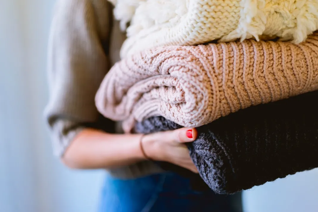 woman with freshly folded laundry sweaters