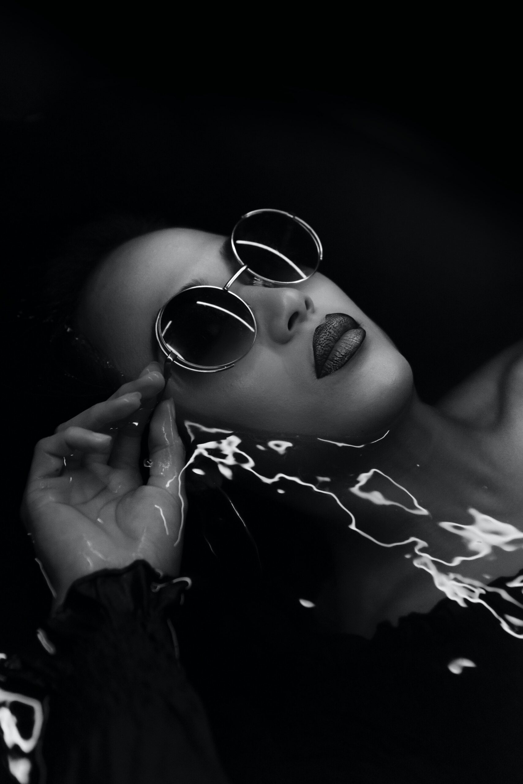 Black model wearing sunglasses in water