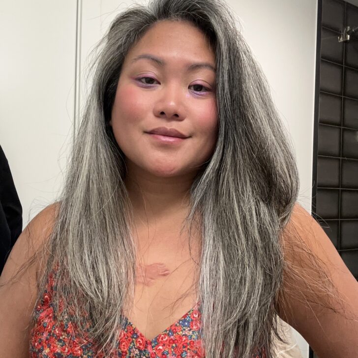 Asian woman with gray hair using DigitalAire hair dryer by Conair